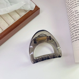 Detailed macro view of translucent smoke grey hair claw clip with golden metal spring