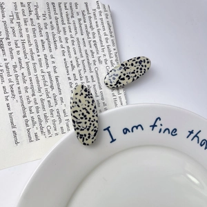 Detailed close-up of oval terrazzo acetate hair clips with stylish black marble pattern
