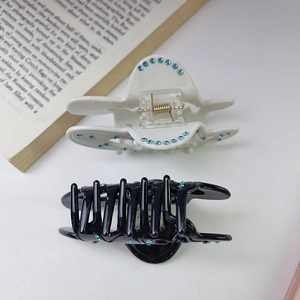 Detail view of black and cream acetate butterfly hair claws with blue rhinestone accents