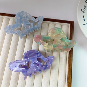 Three acetate butterfly hair claws with hollow design and marble textures on velvet tray