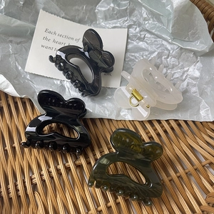 High-quality butterfly hair claws in four colors shown in a cozy wicker basket