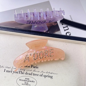 Detail of premium acetate hair claws in pastel purple and pink with rhinestone letters