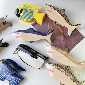 Flat lay detail showing various ocean animal shaped acetate hair clips on a white surface