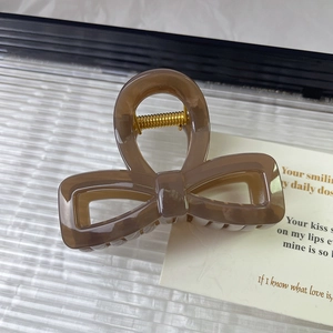 Macro detail of brown marble acrylic bow hair claw with gold metal spring mechanism