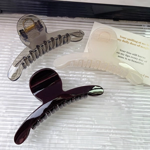 Dettaglio di eleganti mollette per capelli in grigio, bordeaux e crema su fondo ondulato