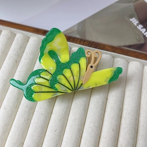 Détail d'une pince à cheveux papillon créative avec paillettes sur un plateau blanc