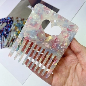 Detailed close-up of heart-shaped cutout acetate hair comb with pearlescent pink texture