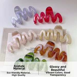 Détail de pinces à cheveux en acétate ondulé de différentes couleurs sur un plateau