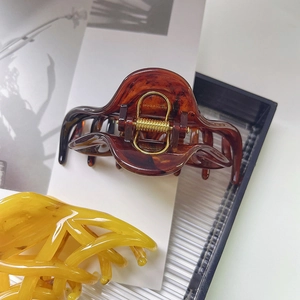 Elegant tortoiseshell claw clip and yellow hair clamp on a minimalist magazine background
