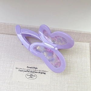 Macro detail of butterfly hair claw clip with purple shell texture and metal spring