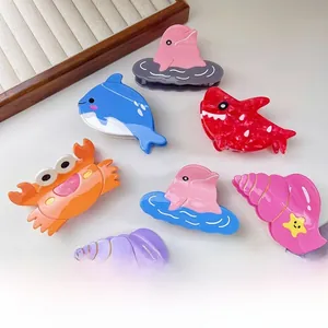 Detailed view of ocean-themed acetate hair claws featuring glossy dolphin and shark shapes