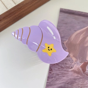 Detail of purple conch hair claw clip with yellow starfish element on resort magazine