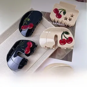 Detail view of acetate cherry hair claws with rhinestones in black and beige colors