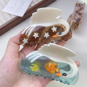Detailed view of handmade acetate swan and ocean fish hair clips with shell patterns