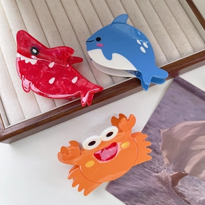 Ocean animal hair claws including pink dolphin and orange crab on a velvet tray
