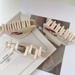 Detailed view of three-piece cherry hair claw set in cream acetate with rhinestone accents