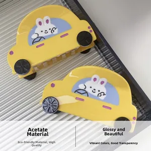 Detail view of yellow acetate car-shaped hair claws with cute cartoon rabbit patterns