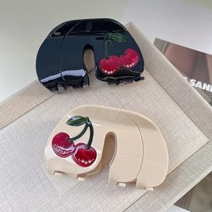 Detailed view of acetic acid hair claw clip with crystal cherry patterns on a soft tray