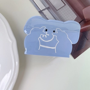 Dettaglio di una grande pinza per capelli in acetato blu con un simpatico koala