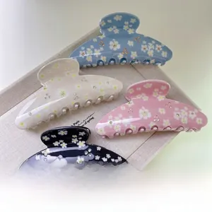 Détail de quatre pinces à cheveux en acrylique avec fleurs et strass en couleurs variées