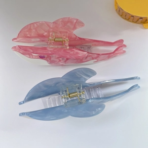 Detalle de pinzas para el cabello de delfín con textura de mármol y resortes dorados