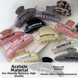 Assortimento di mollette per capelli in acetato a cuore e geometriche su vassoio beige