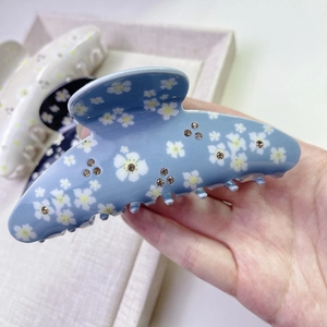 Gros plan sur la pince à cheveux bleu ciel avec motifs floraux blancs et strass