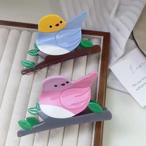 Chic acetate hair claws featuring a bird on a branch design in pastel colors