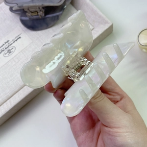Dettaglio macro di una grande molletta per capelli in acetato crema con finitura perlata e denti
