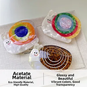 Three acetate snail hair claws featuring tortoiseshell and rainbow patterns on linen fabric