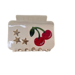 Creamy beige acetate hair claw clip with red rhinestone cherry and star cutout patterns