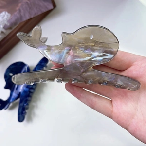 Detailed macro view of whale-shaped acetate hair claw clip with pearlescent finish