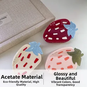 Détail de trois pinces à cheveux en forme de fraise en acétate rouge, crème et rose