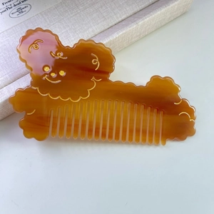 Détail d'un peigne en acétate en forme d'ours mignon avec gravure faciale dorée