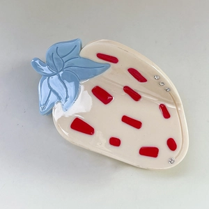 Détail d'une pince à cheveux fraise crème avec feuille bleue et strass brillants
