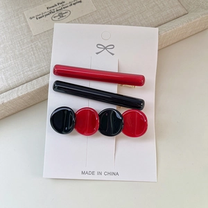 Vue détaillée de trois barrettes à cheveux en rouge et noir sur une carte de présentation
