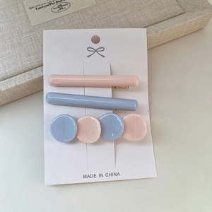 Détail de pinces à cheveux en acétate rose et bleu sur carte avec attache en métal doré