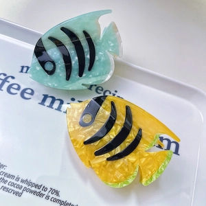 Vibrant fish-shaped acetate hair claw clips in mint green and ginger yellow marble patterns