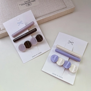 Détail de deux lots de trois barrettes en acétate violet et beige sur supports en carton