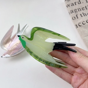 Detailed close-up of bird-shaped acetate hair claw showing smooth texture and green gradient finish