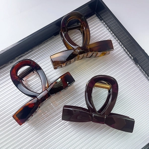 Three-piece bow-knot claw clips in amber and solid brown colors on a black tray