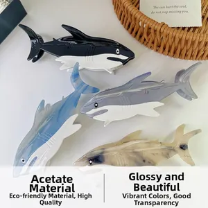 Detail of four acetate shark-shaped hair claws in varied textures on a minimalist desk