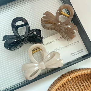Pinces à cheveux épaisses en forme de nœud noires, ambrées et crème sur un plateau