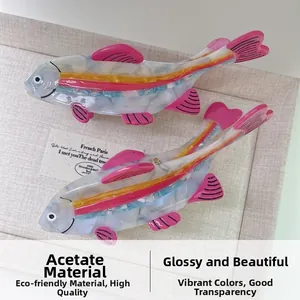 Detailed close-up of two fish-shaped acetate hair claws with pink fins and high-gloss finish