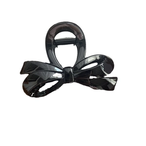 Pince à cheveux nœud noir brillant pour chignons élégants sur fond blanc épuré