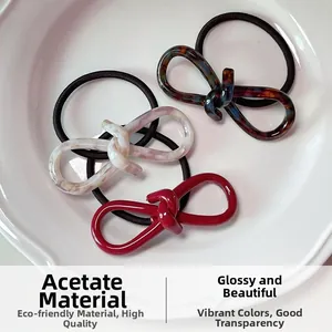 Detail view of high-quality acetate bow hair ties in a ceramic tray showing shiny texture