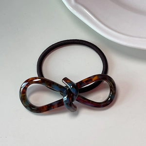 Detailed macro view of an amber cellulose acetate infinity knot hair tie on white ceramic