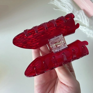 Detail of a large translucent red acrylic hair claw clip with strong metal spring
