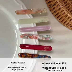 Set of six acetate hair barrettes in floral and solid colors displayed on a ceramic tray