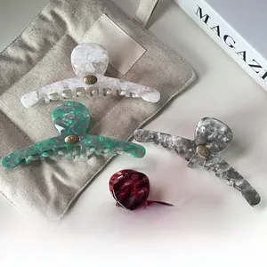 Détail de pinces à cheveux en acétate aux motifs marbrés et écaille avec disque métallique